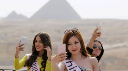 Un grupo de misses se toman varios selfis frente a las pir&aacute;mides de Egipto. 