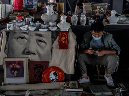 Un hombre con mascarilla vende recuerdos de la era de Mao en un mercado de Pekín