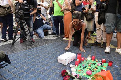Una dona plora al costat de les primeres flors i espelmes col·locades en homenatge a les víctimes de l'atemptat a Barcelona.