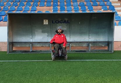 Carlos posa en el banquillo local de su lugar de trabajo: un campo de fútbol.