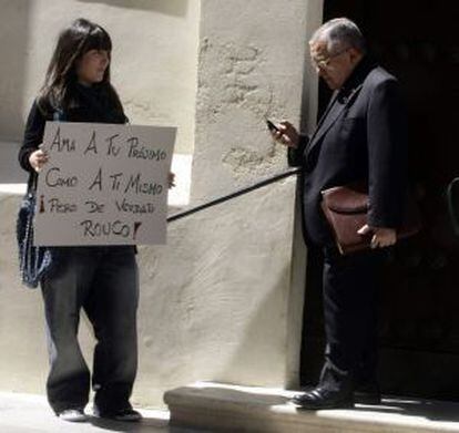 Una indignada del 15-M espera con un cartel a las puertas del Oratorio de San Felipe Neri en C&aacute;diz, a que salga el presidente de la Conferencia Episcopal Espa&ntilde;ola Antonio Rouco Varela.
 