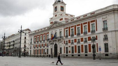 Un hombre pasea con su perro por la Puerta del Sol, junto a la sede del Gobierno de Madrid.