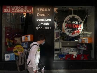 Un hombre pasa por el escaparate de un comercio que anuncia descuentos por el Black Friday, a 12 de noviembre de 2021, en Madrid.