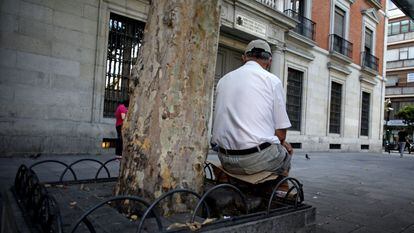 Un hombre sentado sobre las forjas de una jardinera en Madrid.