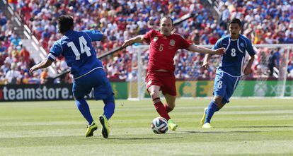 Iniesta se abre paso entre dos jugadores rivales.