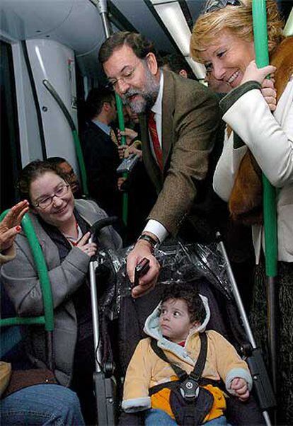 Mariano Rajoy enseña una foto de sus hijos a un niño, mientras viajaba en el metro junto a Esperanza Aguirre.