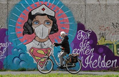 Una mujer monta en bicicleta, en Hamm, al oeste de Alemania, junto a un mural de una enfermera en el que se lee: "Para los verdaderos héroes".
