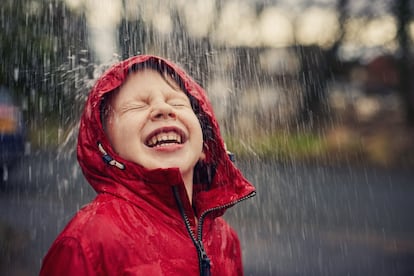 Un niño disfruta con entusiasmo de la lluvia.