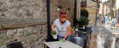 Una trabajadora desinfecta la mesa de la terraza un local de hostelería.