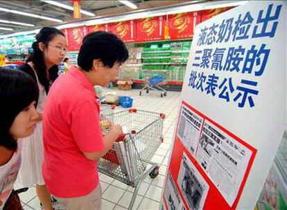 Un grupo de clientes lee un aviso sobre las marcas de leche contaminada en un supermercado de Qingdao, en la provincia de Shangdong (este).