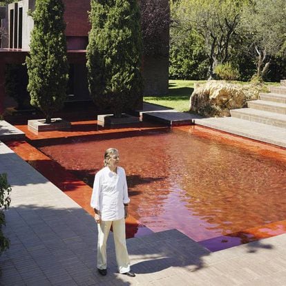 Ricardo Bofill junto a la piscina roja. Tras los cipreses la estructura cúbica acristalada, también roja, hace las veces de comedor.