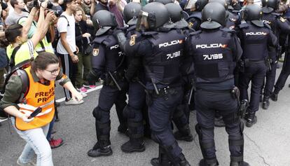 Una periodista identificada amb una armilla cobrint una càrrega policial durant el referèndum il·legal.
