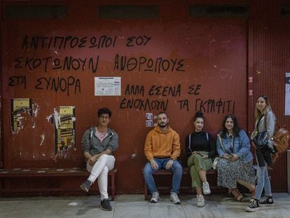 De izquierda a derecha: los estudiantes Stefanos, Alexandros, Eva, Mariana y Katerina, el jueves 18 de mayo en la facultad de Economía y Sociología de Atenas. La pintada de la pared dice: “Tus representantes matan a personas en las fronteras, pero a ti lo que te molesta son los grafitis”.