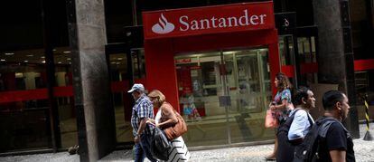 Gente caminando delante de una oficina de Banco Santander