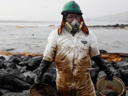 Un hombre trabaja en la limpieza de una playa peruana afectada por el vertido.