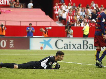 Sergio Rico retiene el bal&oacute;n en el suelo junto al defensa del Barcelona Gerard Piqu&eacute;.