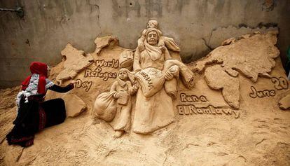 La escultora de arena palestina Rana Ramlawi finaliza una nueva creación artística que conmemora el Día Mundial de los Refugiados en la ciudad de Gaza el 20 de junio de 2020. Su obra representa a una mujer que lleva a una niña niña de la mano y un saco de harina con el logotipo de la Agencia de Obras Públicas y Socorro de las Naciones Unidas para los Refugiados de Palestina (UNRWA) y también un niño sobre sus hombros sosteniendo un bidón de agua, ante un mapa del mundo.