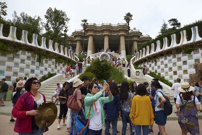 Numerosos turistas pasean por la zona monumental del Park Güell de Barcelona.
