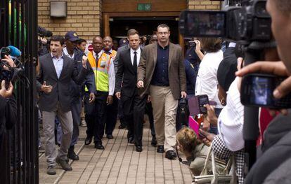 Pistorius (en el centro, con corbata), al salir hoy del tribunal.