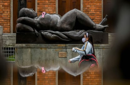 Una mujer pasa frente a una estatua con un lazo rosa, el símbolo del cáncer de mama.