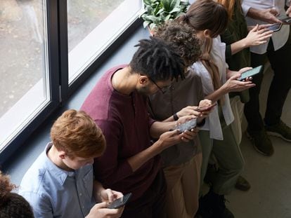 Un grupo de jóvenes maneja sus teléfonos móviles.