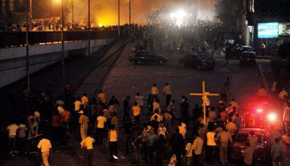 Cristianos coptos (abajo) se enfrentan a fuerzas de seguridad egipcias (arriba) mientras una multitud corre en un puente durante protestas llevadas a cabo frente al edificio de la radiotelevisi&oacute;n en El Cairo.