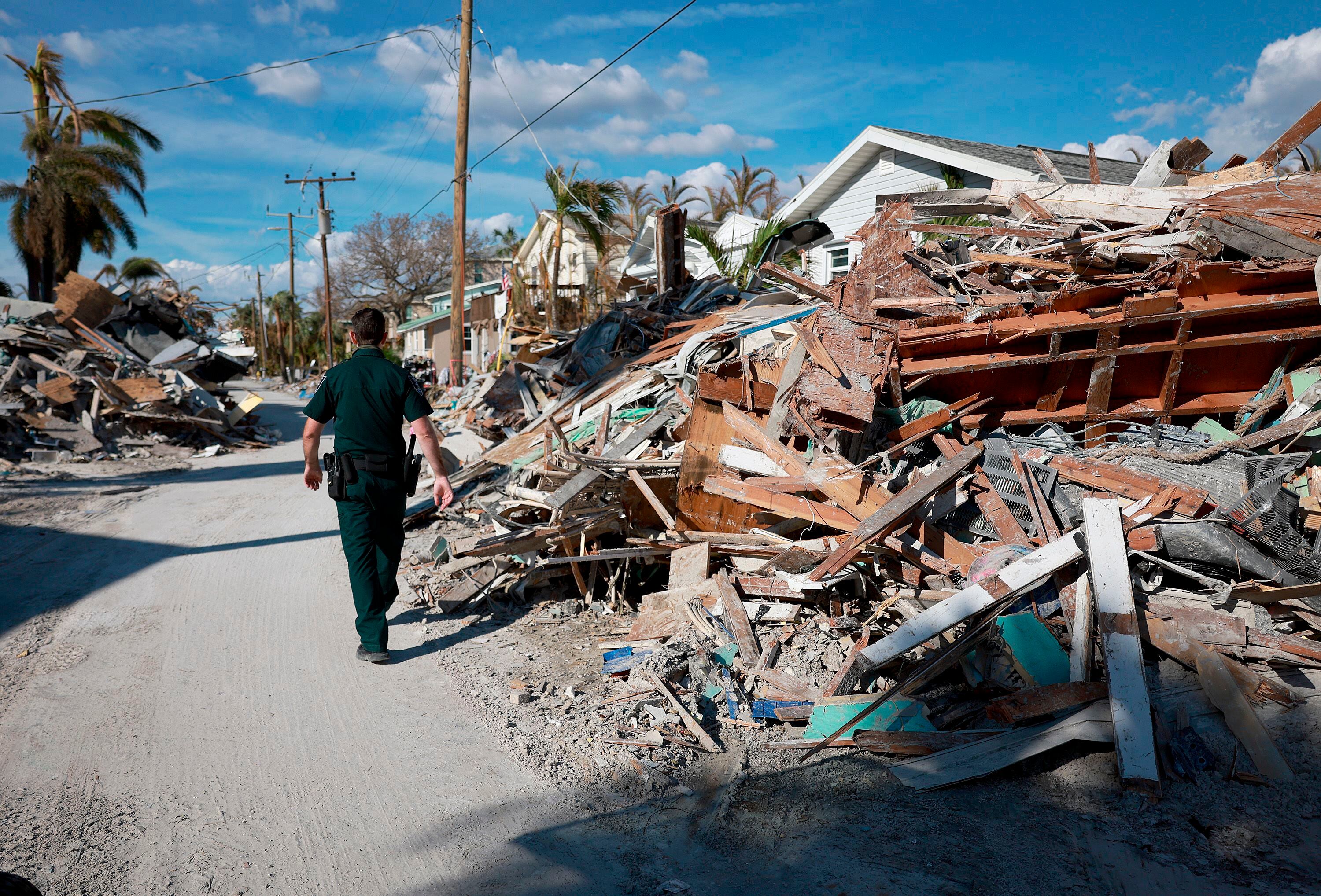 Un sheriff del condado de Lee en Florida camina ente los escombros que ha dejado a su paso el huracán 'Ian'. 