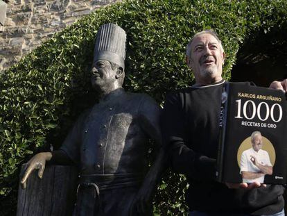 Karlos Arguiñano posa con su último libro junto a una estatua erigida en su nombre en Zarautz (Gipuzkoa).