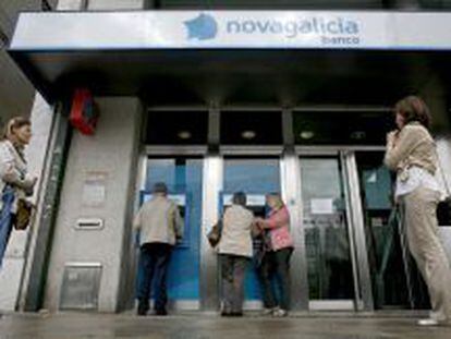 Varias personas esperan para sacar dinero de los cajeros de una sucursal de Novagalicia Banco. EFE/Archivo