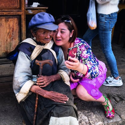 En 'Los secretos de la fotografía de viajes', el fotoperiodista proporciona algunas pistas a la hora de retratar personas. Por ejemplo, explica que antes de intimidar con la cámara a un desconocido hay que intentar establecer unos minutos de conversación, para saber sobre él y darle la oportunidad de relajarse. También es mejor dirigir al modelo, y para el fotógrafo además es una buena técnica contar en alto hasta tres para que éste levante la mirada. Y hay que revisar las fotos cuando uno cree que ya tiene lo que quería, nunca antes. <br> <br>En la imagen, una anciana de la etnia baisha contempla un retrato que le ha tomado una turista con su móvil, en Lijiang (China).</br>