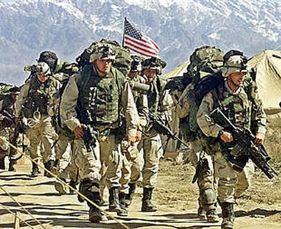 Soldados estadounidenses armados y con mochilas caminan por una base