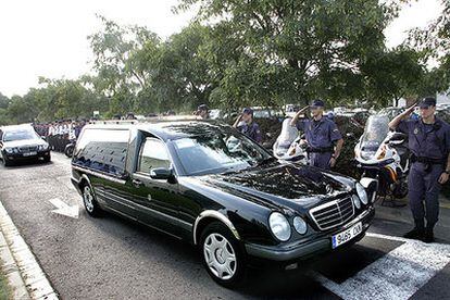 Miembros del Cuerpo Nacional de Policía saludan en L&#39;Hospitalet a los coches fúnebres con los cadáveres de las dos agentes.