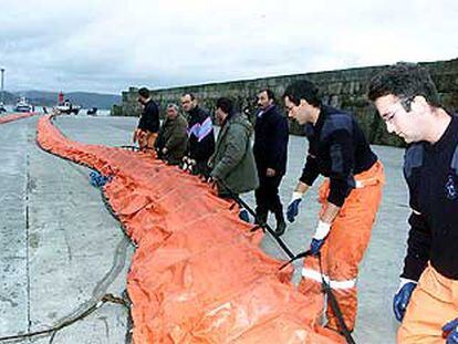 Personal de Protección Civil prepara las barreras de contención del fuel en el puerto de Fisterra.