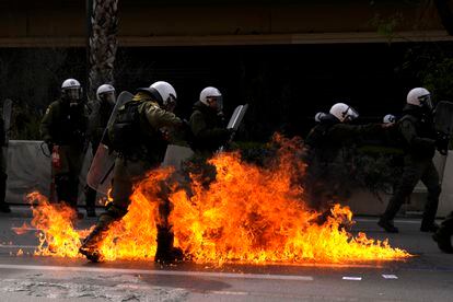 Las llamas de los 'cócteles molotov' lanzados por los manifestantes rodean a un grupo de agentes de la policía antidisturbios, durante la huelga general en Atenas este jueves.  
