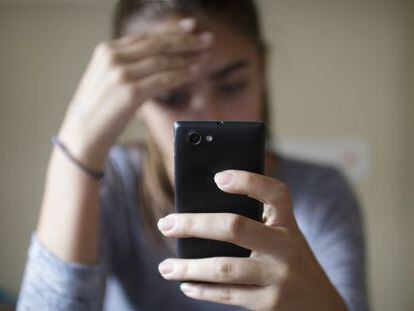 Una adolescente cabizbaja tras recibir una amenaza a través de su móvil.