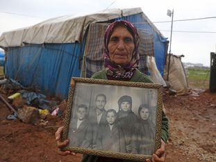 Una desplazada siria muestra una foto familiar en una aldea de Idlib.