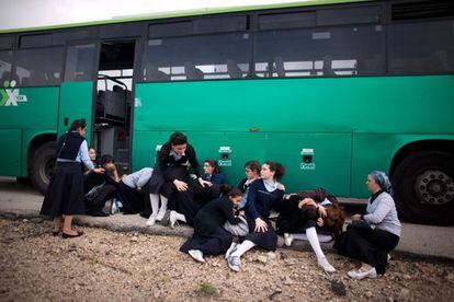 Unas escolares se refugian detrás de un autobús durante el ataque con cohetes lanzados desde Gaza a Ashdod.