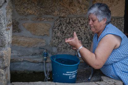 Una vecina de San Mamede, en Porqueira (Ourense), llena un cubo de agua cuyo suministro ha sido limitado a dos horas al día.