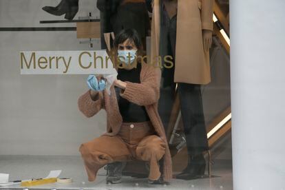 Una mujer prepara el escaparate de su tienda en el centro de Madrid para la campaña navideña.