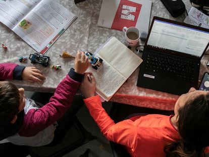 Una mujer teletrabajando junto a su hijo.