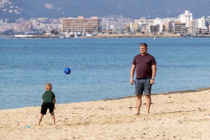 Un hombre juega con su hijo este viernes en la playa de La Palma.