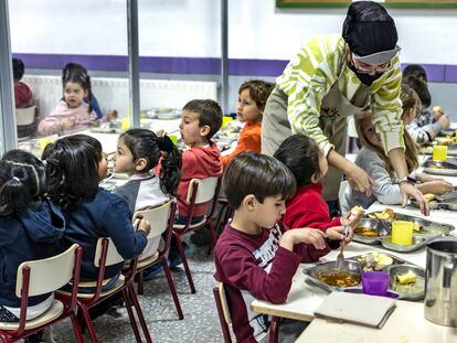 Una monitora atiende a los alumnos del colegio El Grau, de Valencia, durante la hora del comedor.