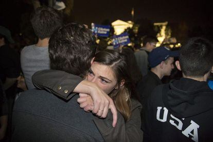 Una pareja simpatizante de la candidata presidencial demócrata, Hillary Clinton, se abraza entre un grupo de personas reunidas frente a la Casa Blanca en Washington DC.