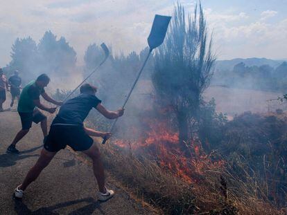 Vecinos intentan apagar el incendio en un camino cerca de Verín, este jueves.