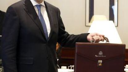 El presidente del Gobierno en funciones, Mariano Rajoy, posa con su maletín oficial tras formalizar su acta como diputado.