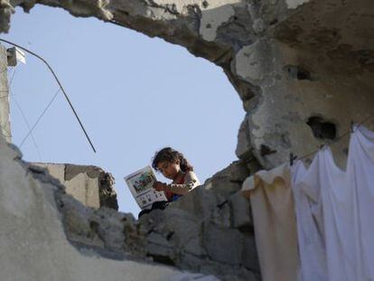 Una ni&ntilde;a palestina lee un libro el pasado s&aacute;bado en el tejado de su casa destruida en la ofensiva de Israel sobre Gaza. 