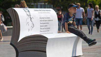 Un niño sentado en un libro gigante con un poema de Alexander Pushkin.