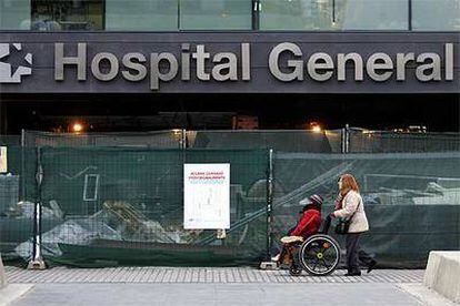 Dos personas pasan por delante del acceso principal al hospital general, cortado por unas obras de remodelación del complejo médico.