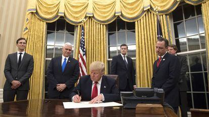 Donald Trump firma en el Despacho Oval frente a las nuevas cortinas doradas.