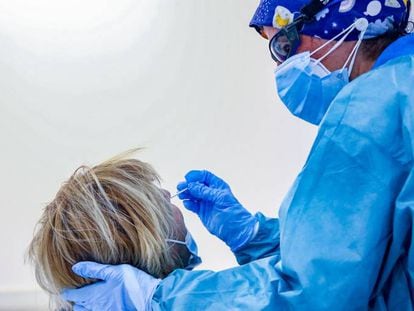 Un sanitario toma muestras a una mujer a través de un frotis de nariz para realizar un test de antígenos.